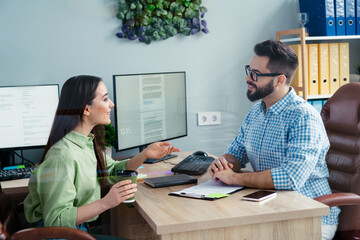 Photo of positive smiling coworkers wear shirts communicating drinking coffee indoors workplace workstation