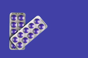 two blisters with blue tablets on a blue background with copy space