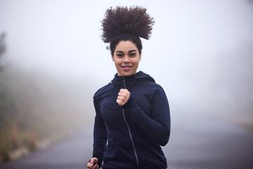 Girl, running and smile in morning fog in nature for health, fitness or wellness on road in...