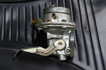 Fuel pump from an old carburetor gasoline engine of a USSR car on black background. Moskvich