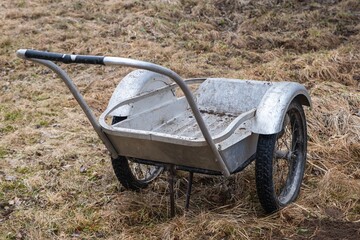 A wheelbarrow with a tire is parked on grass in a field