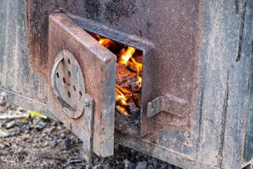 a close up of a rusty stove with a fire coming out of it