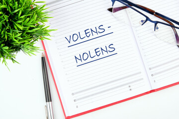 Willy - nilly latin expression volens-nolens (willing or unwilling) written in a notebook on the...