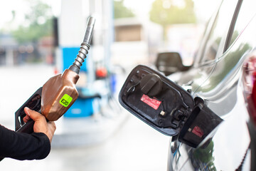 A gas station attendant holds a fuel nozzle at a gas dispenser in a gas station.