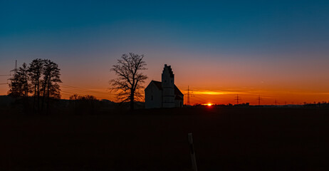 Fototapeta premium Sunset with a church silhouette at Huett, Eichendorf, Dingolfing-Landau, Bavaria, Germany