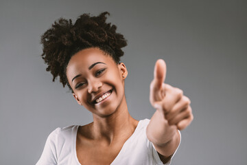 Afro-haired woman gestures success with a smile