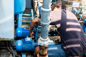 Selective focus to hand of plumber repair and remove motor of centrifugal water pump. Plumbers working to installation centrifugal water pump motor. - obrazy, fototapety, plakaty