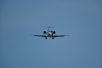 Fototapeta premium Airplane in the blue sky near the airport. The plane is preparing to land
