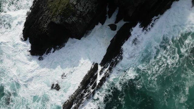Aerial drone shot of foamy sea waves breaking on rocks