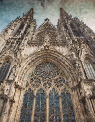 Fototapeta na wymiar Show a detailed architectural facade of a gothic cathedral, emphasizing the complex patterns of stained glass windows and carved stone tracery.