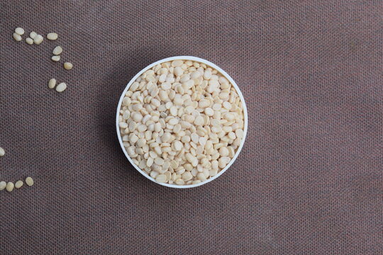 Close up of Organic split polished white urad dal (Vigna mungo) on a ceramic white bowl with the gradient background of urad dal polished. Top view, ماش کی دال ،دال ماش