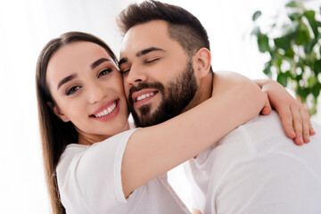 Photo of dreamy good mood husband wife nightwear cuddling smiling indoors house bedroom