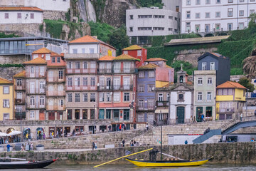 Fototapeta na wymiar Porto, Portugal Skyline, the old town of Porto from across the Douro River. Colorful houses of Porto Ribeira, traditional facades, old multicolored houses with red tiles during a foggy day, Portugal.