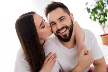 Photo of pretty positive husband wife nightwear kissing cuddling indoors house bedroom