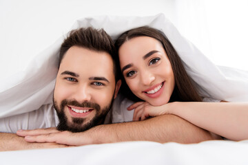 Photo of sweet toothy boyfriend girlfriend sleepwear hugging smiling indoors home bedroom