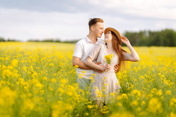 Tender family photo at sunset in the field. Young couple in love walks through a rapeseed field. The concept of love, test, relationship.