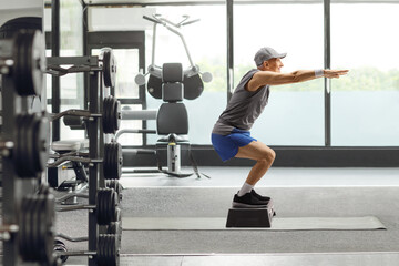 Elderly man working out on a step aerobic platform at a gym
