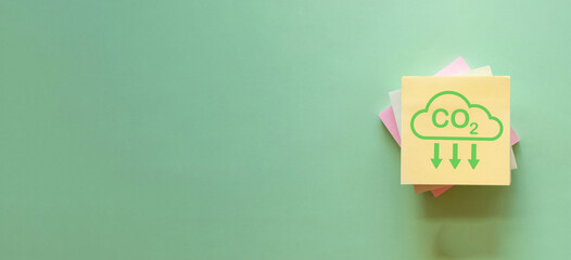 Green Sticky Note Featuring Reduce CO2 Icon against Nature-Inspired Background, Encouraging...