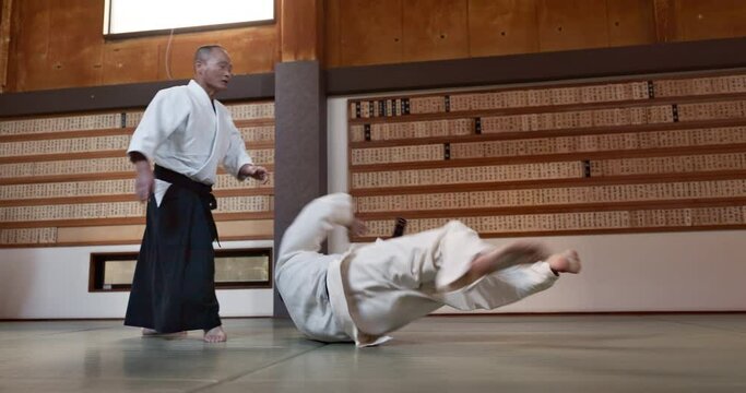 Man in dojo with sensei for aikido training, fitness and development with action, exercise and coaching. Teaching, learning and fight, student in traditional Japanese martial arts class with aikidoka