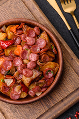 Grilled potatoes cut into slices with hunting sausages with garlic, onion