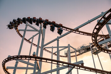 An anonymous player rides a roller coaster with the evening light as the background