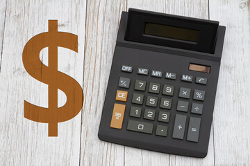 Naklejka premium A black calculator with a gold dollar sign on wood desk