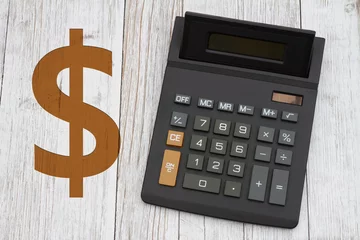   A black calculator with a gold dollar sign on wood desk © Karen Roach