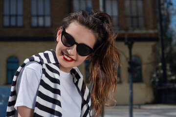 Portrait of a girl with a ponytail and red lips smiling on the street