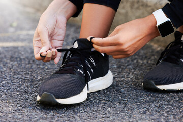 Fitness, hands and tie shoes on road to start workout, training or exercise legs outdoor. Closeup, runner and tying lace on sneakers at street in preparation for sport, health and wellness of woman