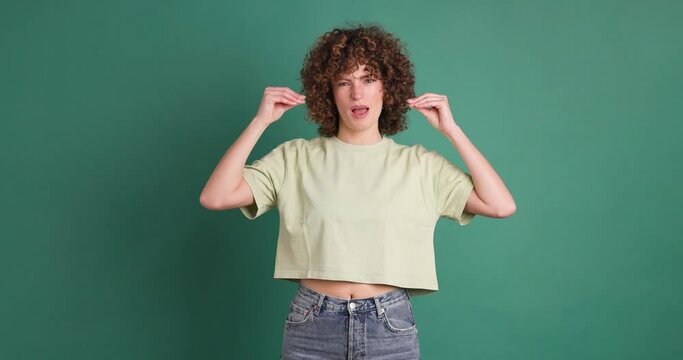 Bored young woman saying blah blah with hands gesture on green background