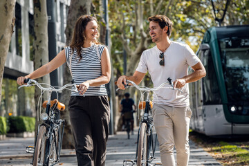 Happy loving couple cycling while looking each other in the city - 790066443