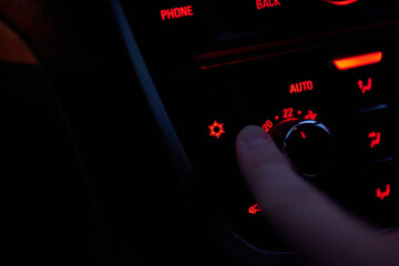 Man hand turns the air conditioner in a car at night. Temperature and blow air conditioner setting