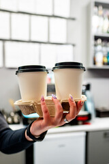 Person holding a tray with two takeaway coffee cups, illustrating a common cafe scene and the on-the-go lifestyle