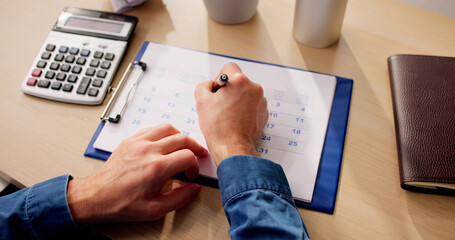 Close-up Of A Businessman's Hand Marking Date On Calendar