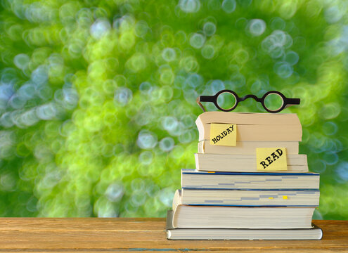 New book releases for spring and summer holiday read, with stack of books, spectacles.blurred background.Vacation,inspiration,relaxation,reading, education, literature concept, free copy space