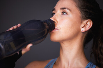 Woman, exercise and drinking water in studio for workout hydration or healthy sports, grey...