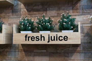 Artificial flowers hanging on the wall with the words fresh juice