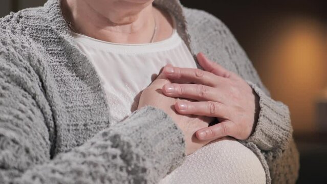 Chest pain. Close-up of elderly woman hands holding her chest. Heart attack, heart failure and heartburn concept