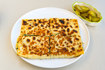 Freshly baked appetizing Turkish tortillas -Gozleme with spinach, cheese  on a wooden board. Shallow depth of  field. Handmade Turkish traditional pastries. Otlu peynirli ispanakli gozleme.