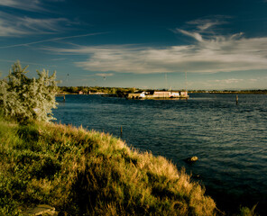 Tranquil waters embrace a picturesque scene of fishing boats and rustic huts along the shores of...