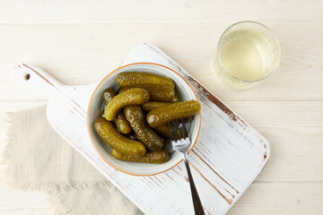 Marinated gherkins in a bowl and pickled juice  , on a white wooden background. Homemade pickles....
