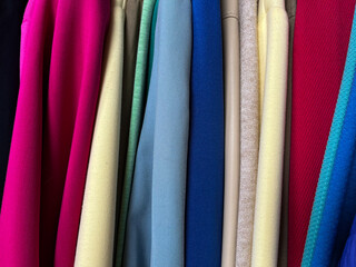 A closeup of a row of colorful jackets. Side view of clothes on a hanger in a store.