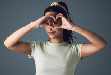 Girl, fashion and eye with heart hand in studio on grey background in casual, style and gen z....