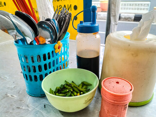 Chili and soy sauce on the dining table with tissue and toothpicks prepared for customers at Indonesia street food stalls. Selective focus.
