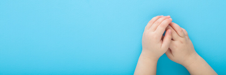 Baby boy hands on light blue table background. Pastel color. Closeup. Point of view shot. Empty place for text. Wide banner. Top down view. - 790103218