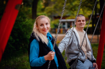 A couple shares a cheerful moment on swing sets, with a gentle focus shift that highlights their...