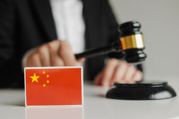 Judge's hand holding wooden gavel. Flag of China. Sanctions in China concept.