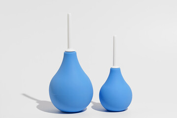 Two blue rubber enemas - larger and smaller on a gray isolated background. The concept of pharmacy,...