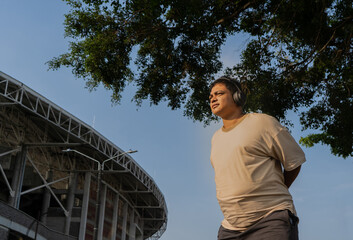 hombre latino mirando a un costado y usando audífonos para realizar su rutina de ejercicio al aire...
