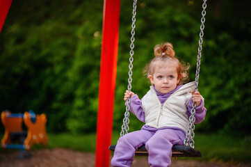 A little one experiences the joy of swinging, her tentative hold and soft focus gaze evoking the newness and excitement of this beloved playground activity